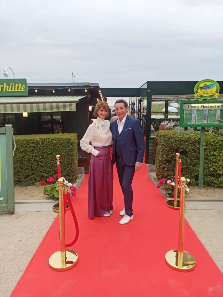 Thomas und Steffi Kühnel von Stilvoll Tanzen stehen auf dem roten Teppich vor Uwes Fischhütte im Seebad Ahlbeck