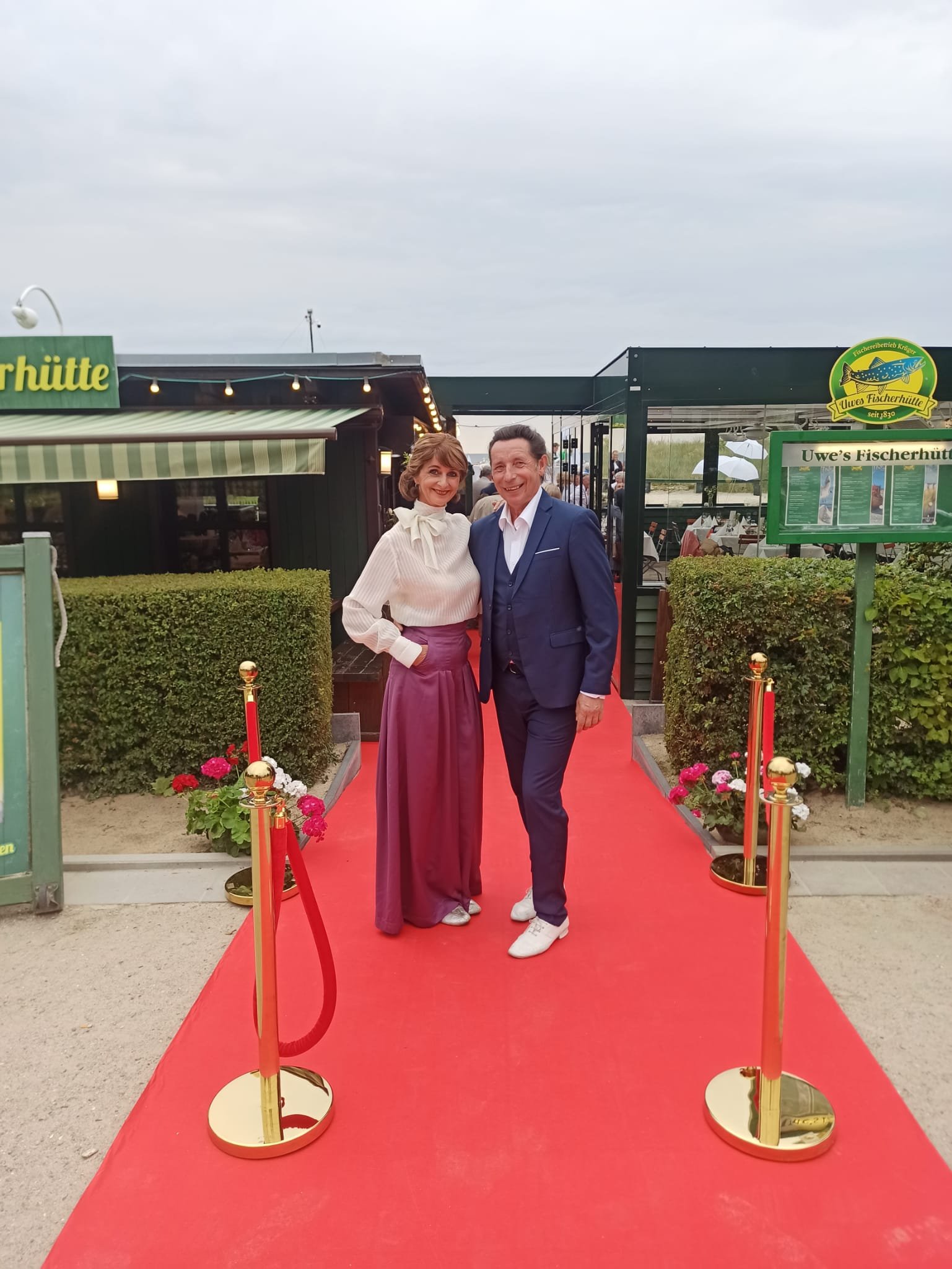 Thomas und Steffi Kühnel von Stilvoll Tanzen stehen auf dem roten Teppich vor Uwes Fischhütte im Seebad Ahlbeck